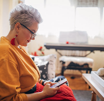 Woman sitting on sofa and using smart phone at home