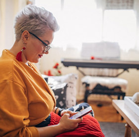 Woman sitting on sofa and using smart phone at home