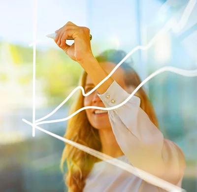 Businesswoman drawing graph on glass while standing at modern office