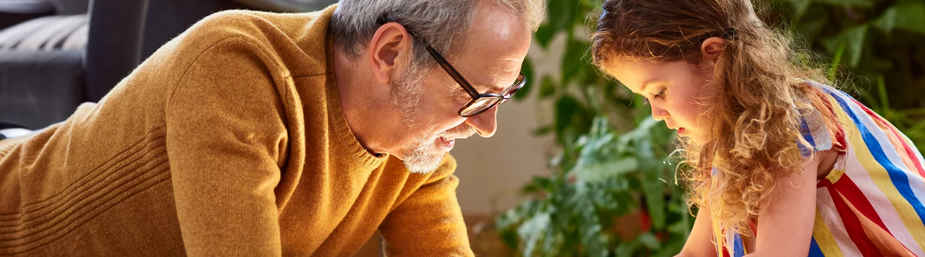 A grandfather watches as the grandaughter plays with wooden blocks