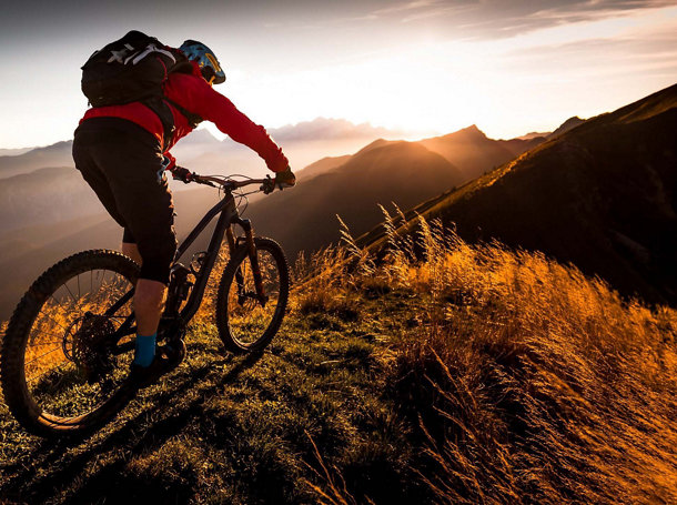 A ready cyclist on the edge of a mountain during the hours of sunris