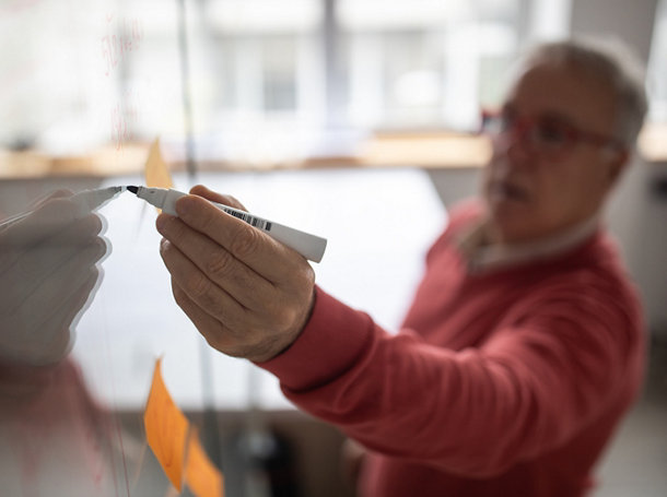 Businessman writing some ideas on glass wall in office