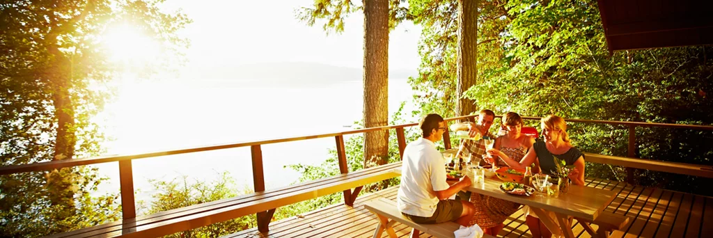 Man pouring wine into woman's glass at sunset