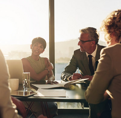 Une femme d’affaires discute de travail avec des collègues autour d’ une table dans une salle de conseil