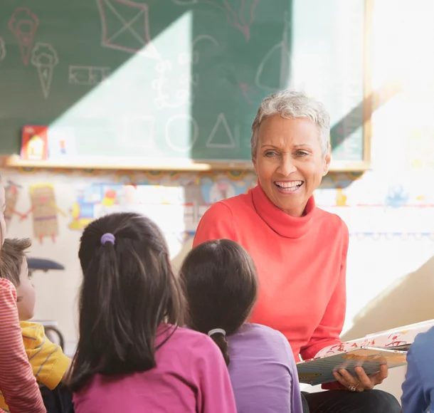 Mixed race teacher reading to students in classroom