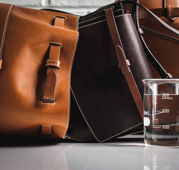 three leather bags next to a glass measuring cup.