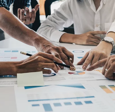 people pointing at charts on a table