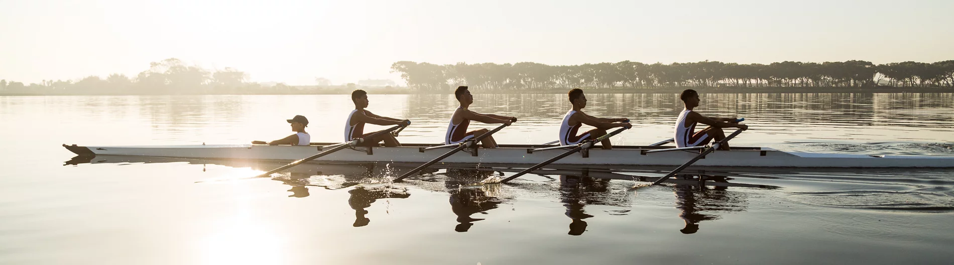 Une équipe d’ aviron multiethnique s’ entraîne sur un lac à l’aube