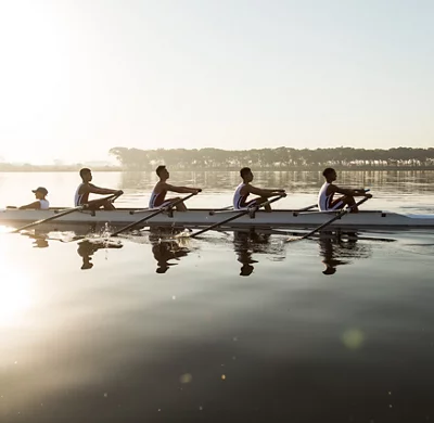 Une équipe d’ aviron multiethnique s’ entraîne sur un lac à l’aube