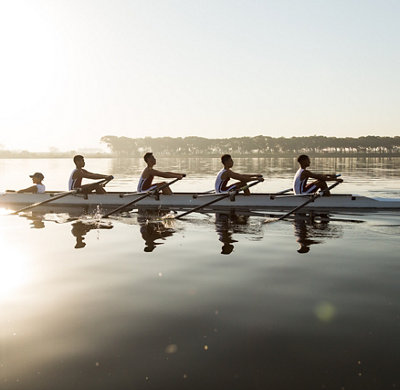 A mixed race team rows in a lake at dawn