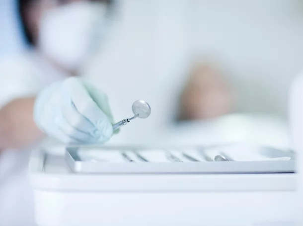 Close up of hand holding dentist mirror