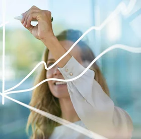 Businesswoman drawing graph on glass while standing at modern office