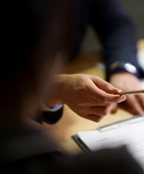 man handing over a pencil to another person