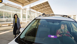 A lyft car with one woman driving and another standing
