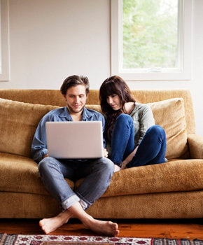 Young couple looking at laptop on couch