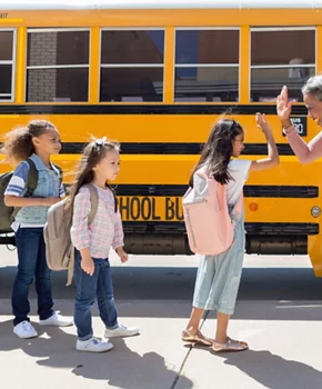 Retired teacher high-fives students in front of school bus