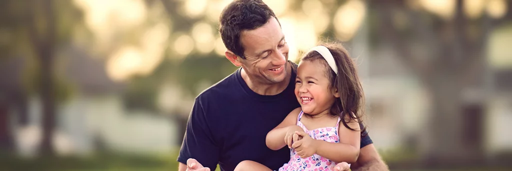 An image representing a father and a daughter laughing and playing.