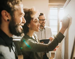 An image representing group of people discussing and writing on a board.