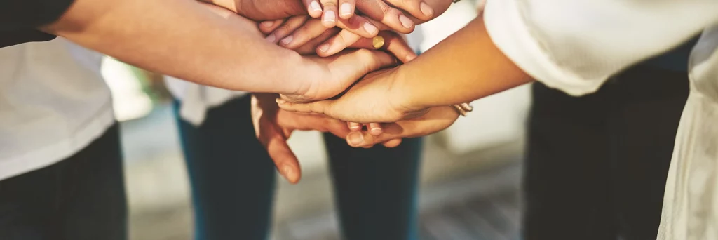 Photo rognée d’un groupe de personnes non reconnaissables joignant leurs mains en signe d’ unité à l’extérieur