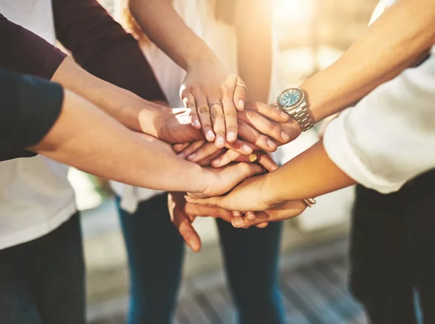 Cropped shot of an unrecognizable group of people putting their hands together in unity outside