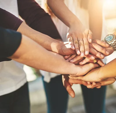 Photo rognée d’un groupe de personnes non reconnaissables joignant leurs mains en signe d’ unité à l’extérieur