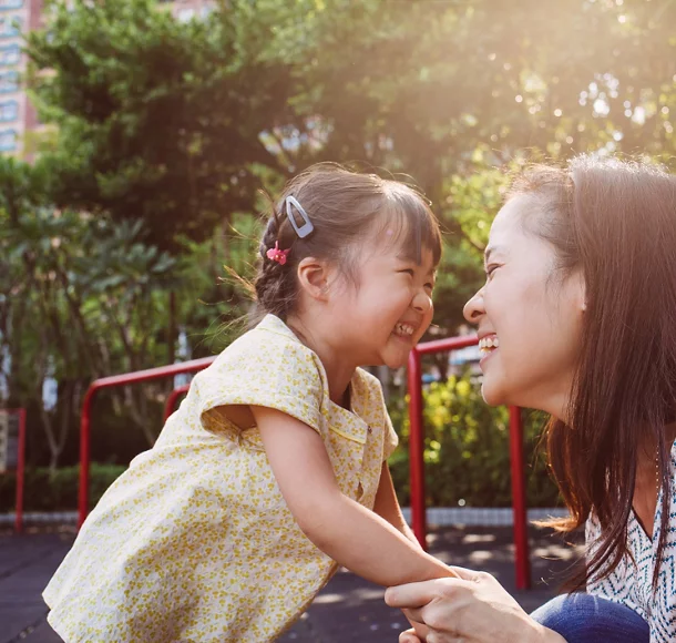 A mother and her daughter laughing in a park