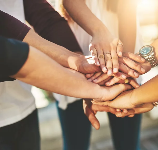 Photo rognée d’un groupe de personnes non reconnaissables joignant leurs mains en signe d’ unité à l’extérieur