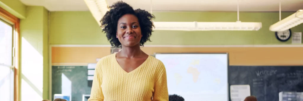 A principal smiles while visiting students in the classroom.