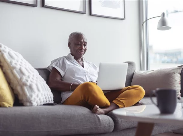 Woman on a grey couch looking at her laptop
