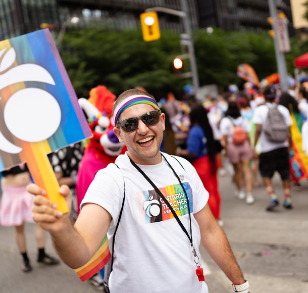 Michael Cherny holding an Ontario Teachers' rainbow sign at the Toronto Pride Parade