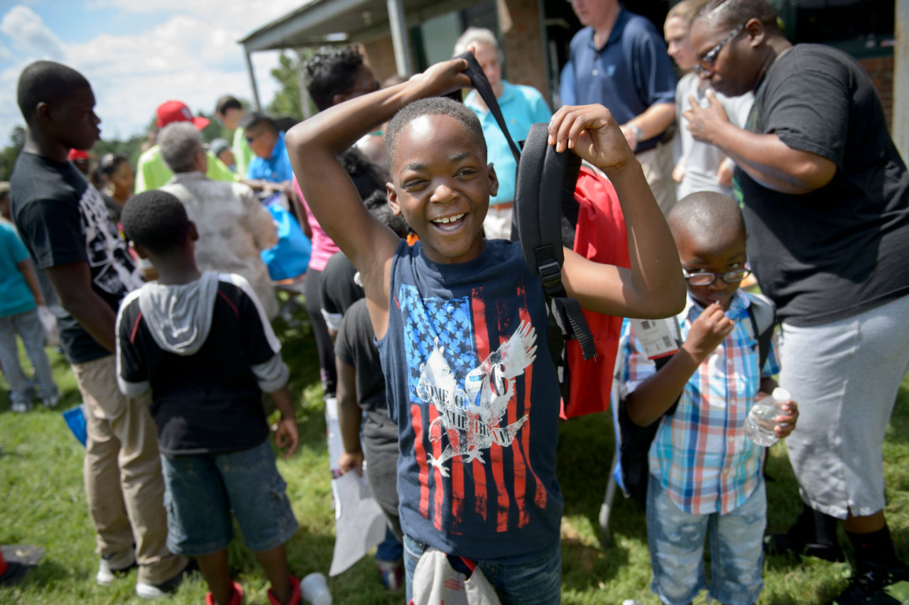 Jaylen Davis, 9, center, tries on his new backpack with the help of Laurence Gray, 9, right, during Beyond Housing's "Beyond the Backpack" event on Saturday, Aug. 6, 2016. The event, held at Normandy High School in Northern St. Louis County, Mo., provided families in the 24:1 communities with back-to-school resources, including immunizations and haircuts. (TRACIE VAN AUKEN/ For the Robert Wood Johnson Foundation)