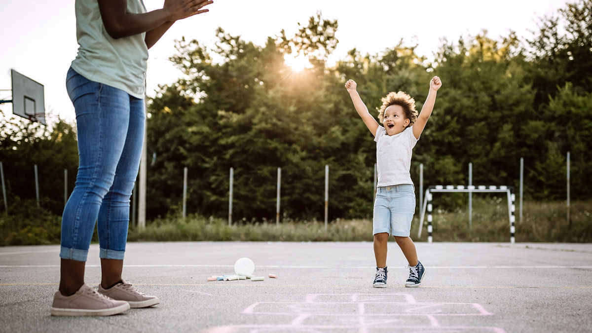 Multi-ethnic group of children playing hopscotch on school yard on summer afternoon