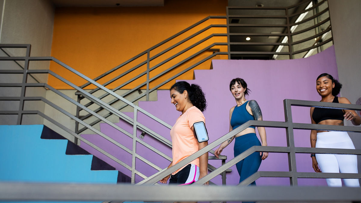 Group of multi-ethnic women walking down the stairs of gym. Three females in sportswear leaving the gym.