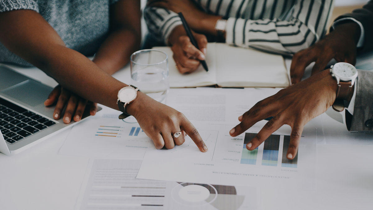 Closeup shot of a group of unrecognisable businesspeople analysing graphs in an office