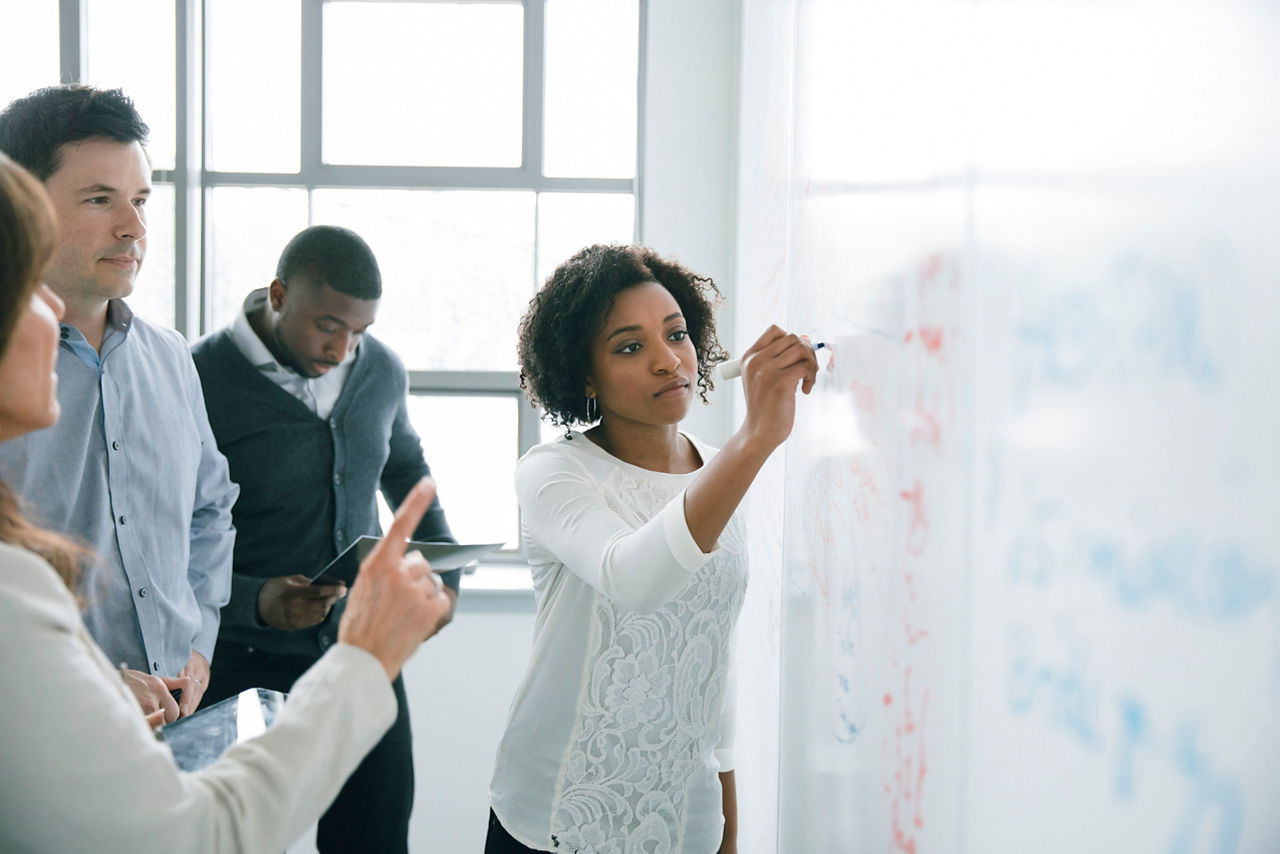 Businesswoman writing on whiteboard in meeting