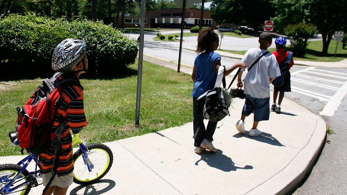 Children crossing street on way to or from school. Some children walking, others riding bikes.  Safe Routes to School at Knollwood Elementary in Decatur, GA.