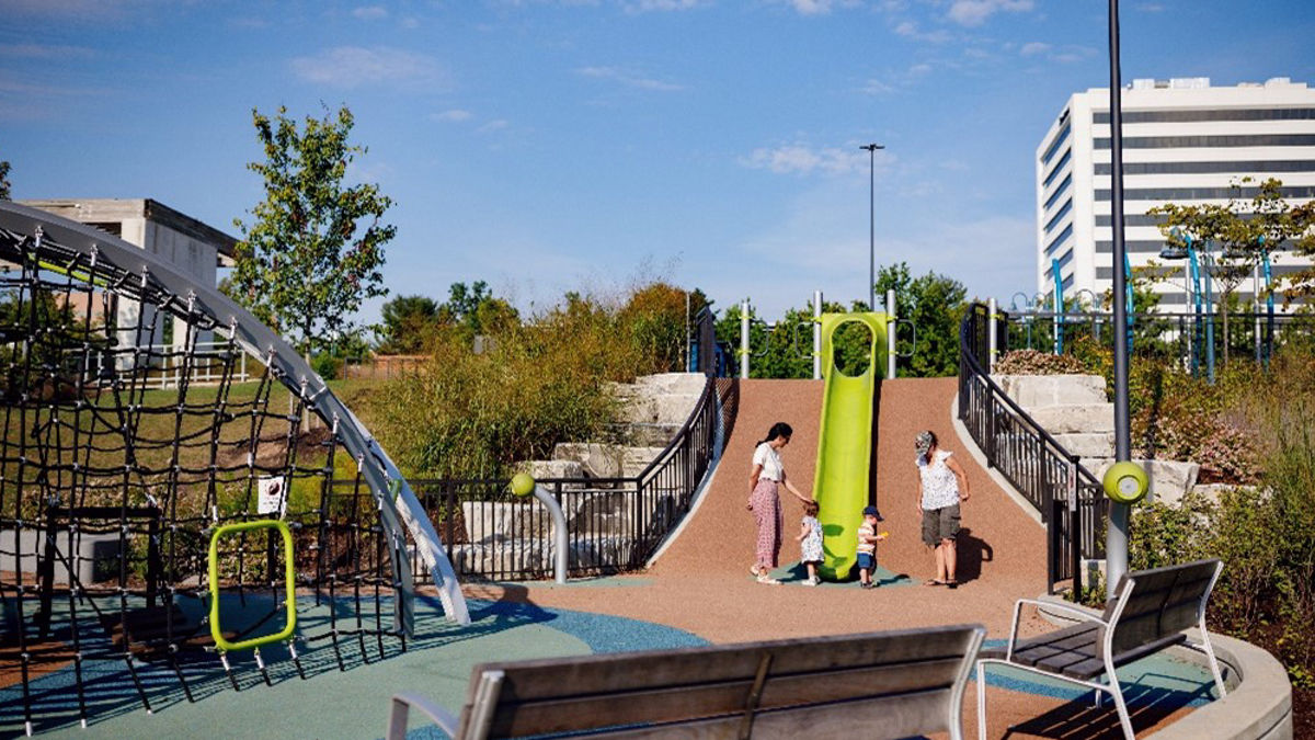 A family plays near a slide at a playground.