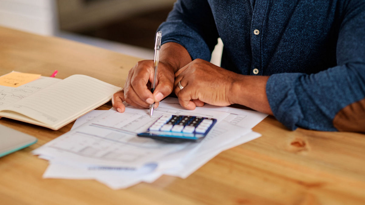 Cropped shot of an unrecognizable mature man calculating and going over his finances at home