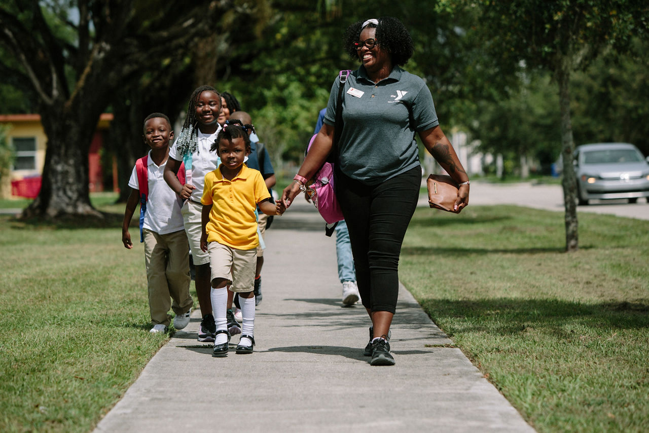 Fort Lauderdale, FL - August 22, 2019 - Members of the Kids Enrichment Club walk to the LA Lee YMCA after school with Jonai Perry (27), a Counselor.