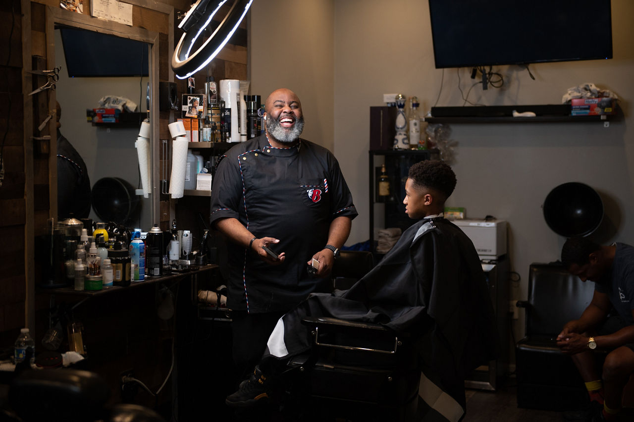 Barber Paul Jones, a member of the More Than a Shop barber and beautician network, cuts a young client’s hair at his shop. As part of the network, Jones helps to connect the  communities where he works with resources to address healthcare disparities, food scarcity, literacy, substance abuse and other issues.