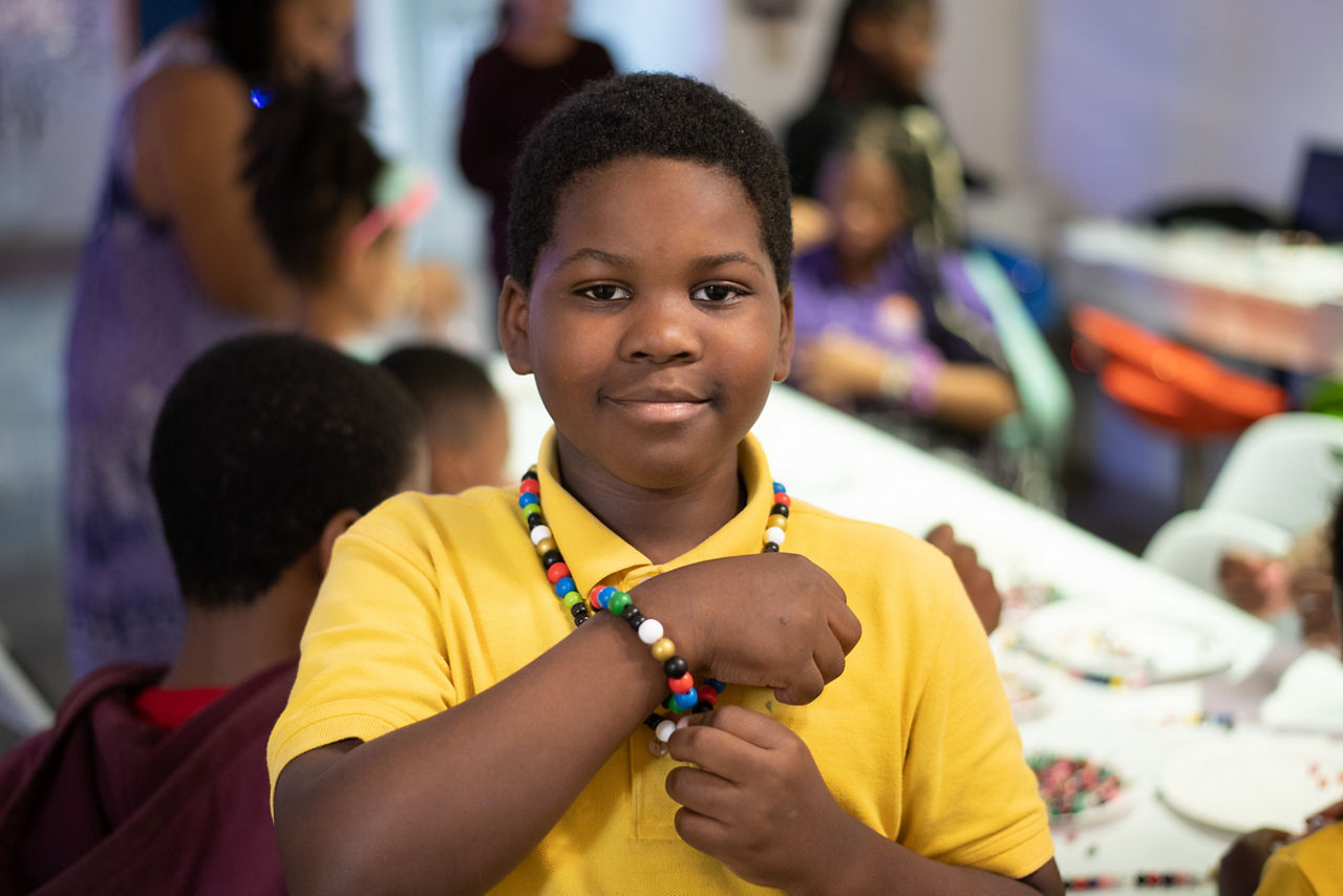 A participant shows off his beaded bracelet and necklace during a beading activity in the Transformation Nation Healing Suites. The Healing Suites were conceptualized and created by therapists Monica Boddie and Cyrus Nusum to act as a therapy hub for Baltimore children dealing with trauma.