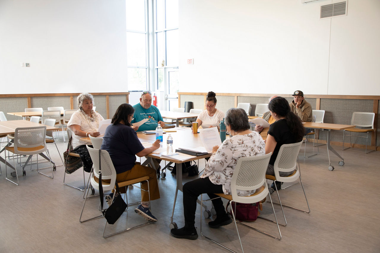 Quarterly Language Advisory Board Meeting held at the Cultural and Language Center in Fond du Lac. (L-R) Dawn Laprairie, Dawn Schulze, Wayne Dupois, Vicki Reynolds, Robert Peacock, Michelle Gouse, and Janis Fairbanks discuss Ojibwemowin language restoration efforts. Nenaaw/Charles Smith, who works at the FDL Cultural and Language Center sitting off to the side taking notes.