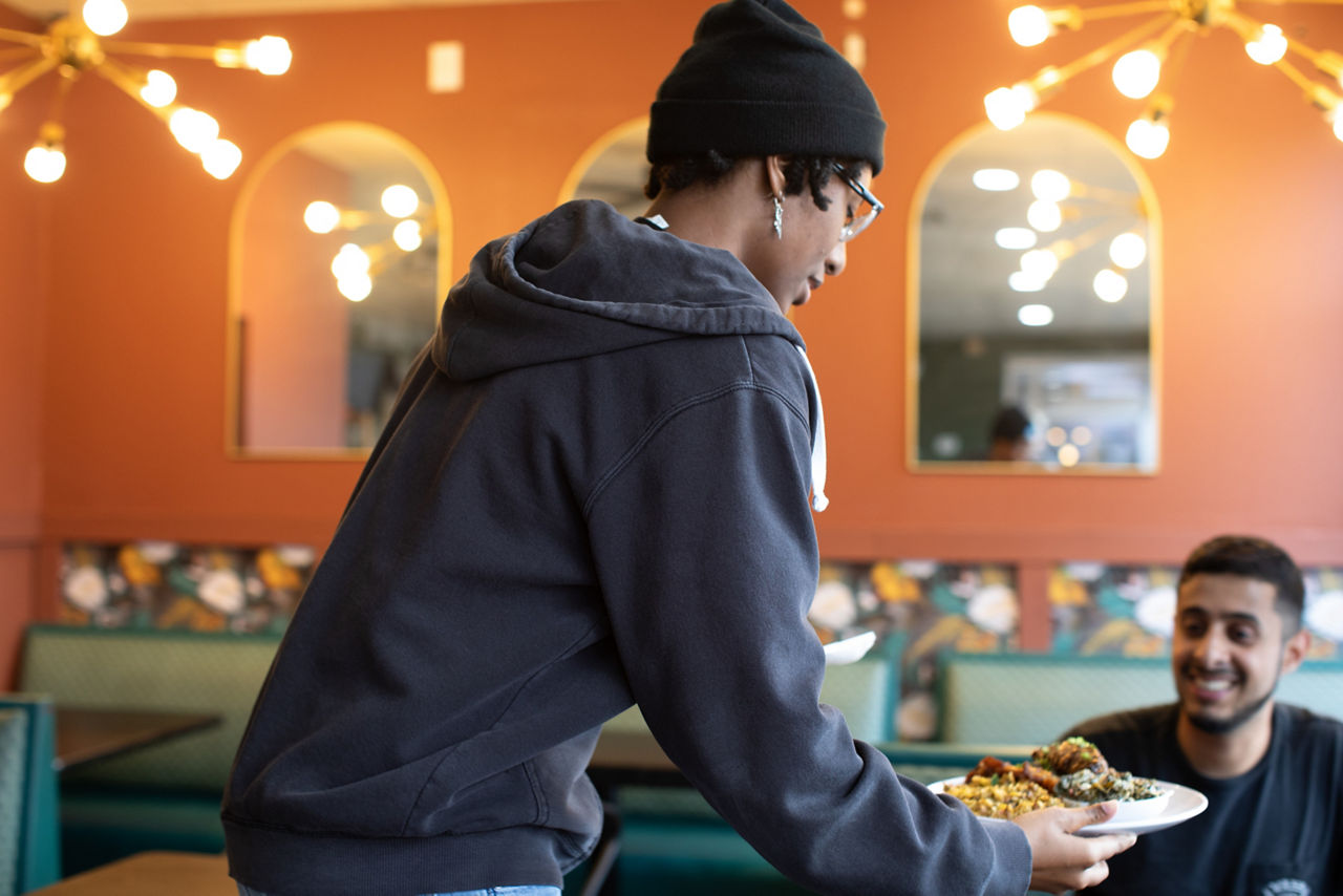 Rea Griggs serves a customer at Kuji Kitchen, an "Island food and coffee" restaurant in the Sunnyside neighborhood of Houston, TX owned by Ivy Walls and Jeremy Peaches, two farmers who run the nearby Ivy Leaf Farms.