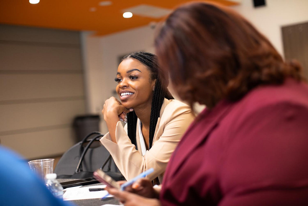 Woman smiling as she talks to other people.