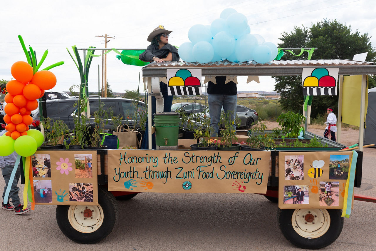 Zuni Youth Enrichment Program (ZYEP) parade float highlighting their food sovereignty work for the 58th Annual Zuni Tribal Fair, the theme of which was "Honoring the Strength of Our Youth." Khassandria Hattie, ZYEP Food Sovereignty Leader featured on the float.