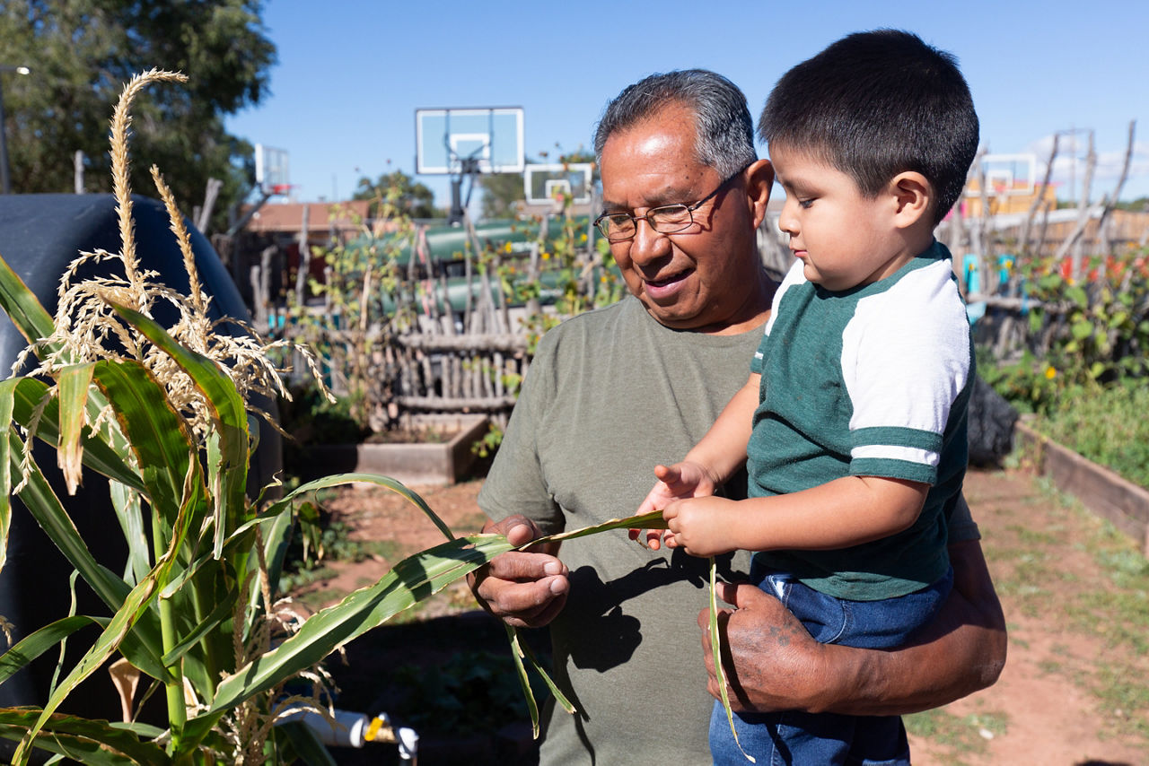 Octavius Seowtewa and his grandson, Taylen, take a stroll in the Zuni Youth Enrichment Project (ZYEP) garden. Intergenerational learning is a cornerstone of ZYEP’s work.