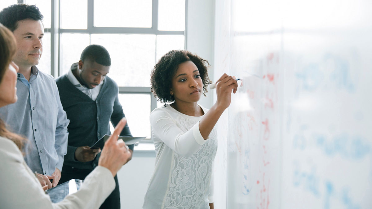 Businesswoman writing on whiteboard in meeting