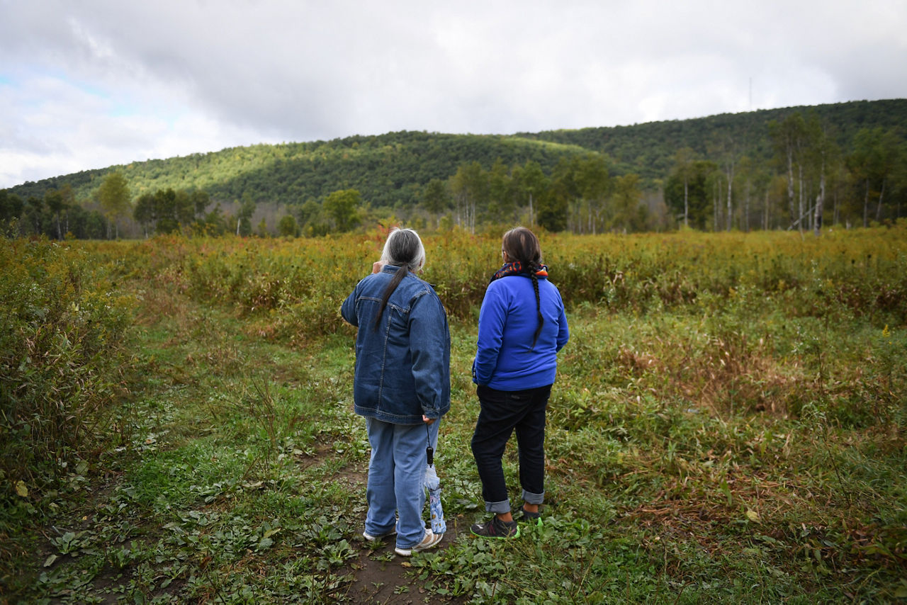 Two woman looking into the distance on a field of greenery.