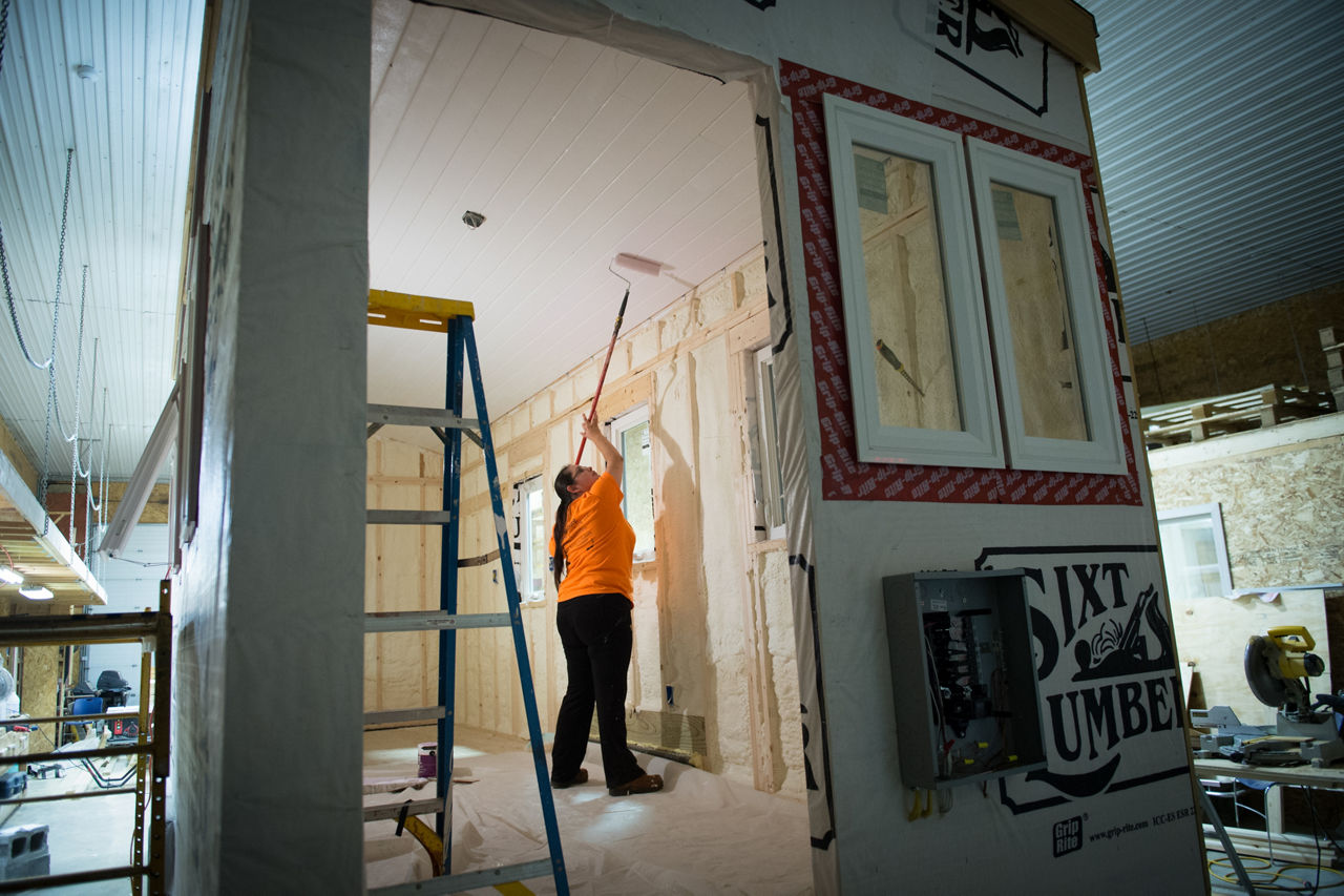Student Krista Cooper paints a tiny house as part of the Construction Technology Program at the Seneca Nation Employment and Vocational Training Center in Allegany. Upon completion the house will provide senior housing and will be entirely self-sustainable and off-grid.