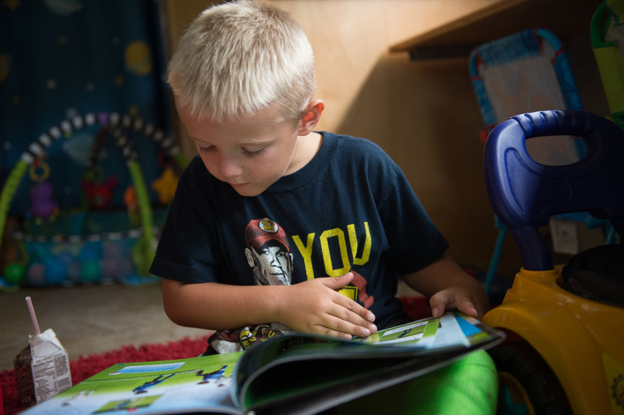 Brantley Lantz, 5, reads and drinks milk on the Learning Beyond the Classroom Bus as it sits in front of Crellin Elementary School. The bus holds a library and learning games for children, and offers healthy snacks.